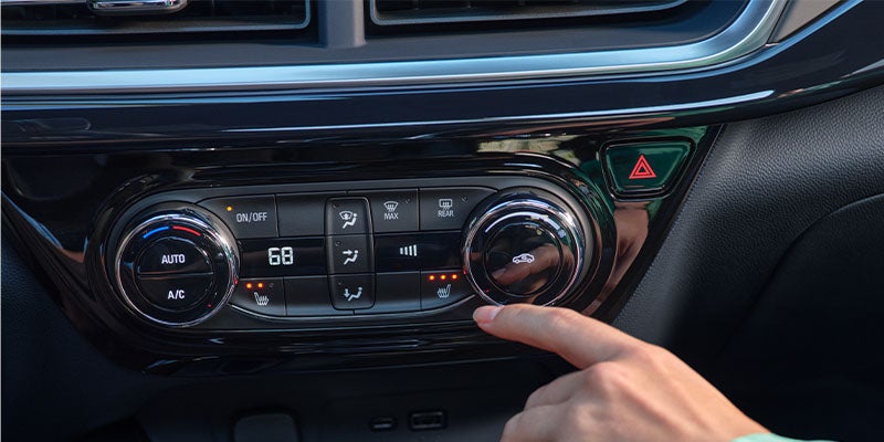 A person using the dashboard buttons in a car,focused on the controls while seated inside the vehicle.